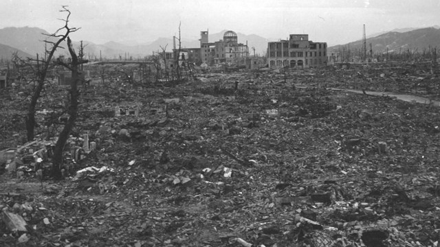 A city reduced to rubble with a large, dilapidated building in the background.