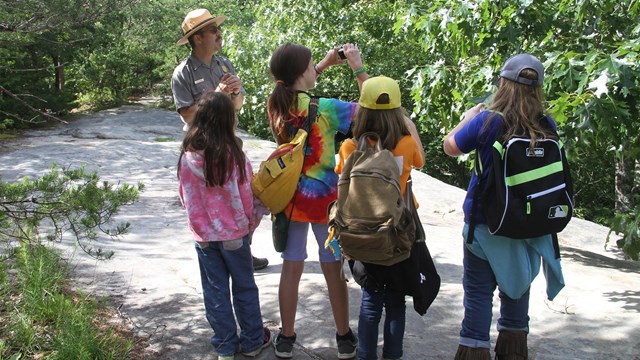 A ranger and four children on an outdoor trail.&nbsp;
