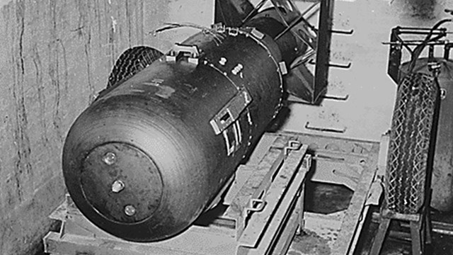 A black and white photo of a cylindrical object with a boxy tail. 