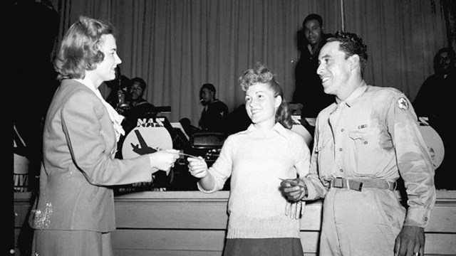 A black and white photo of a couple speaking to another woman.