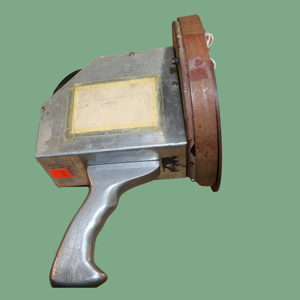 A gun-shaped device in silver and black on a mint green background.