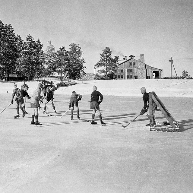 A black and white photo of children playing ice hockey on a frozen pond.