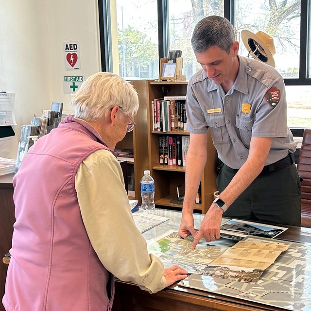 A ranger points to a map for a visitor.