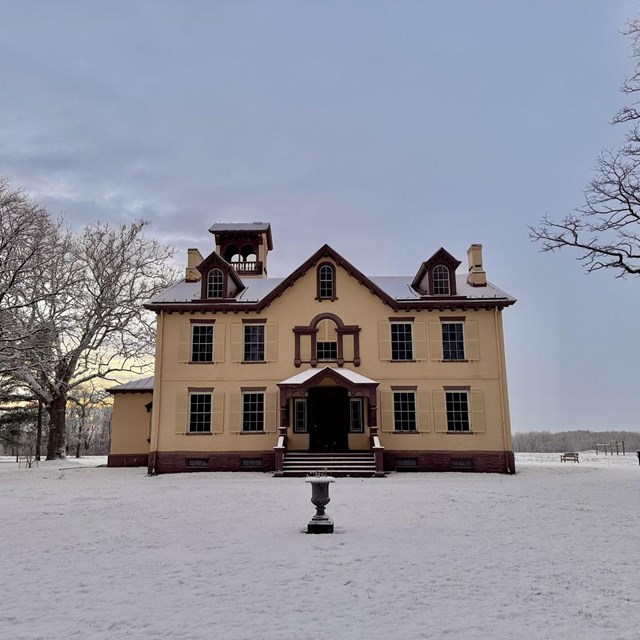 Lindenwald covered in fresh snow on a winter evening, with bare trees and soft light in the sky.