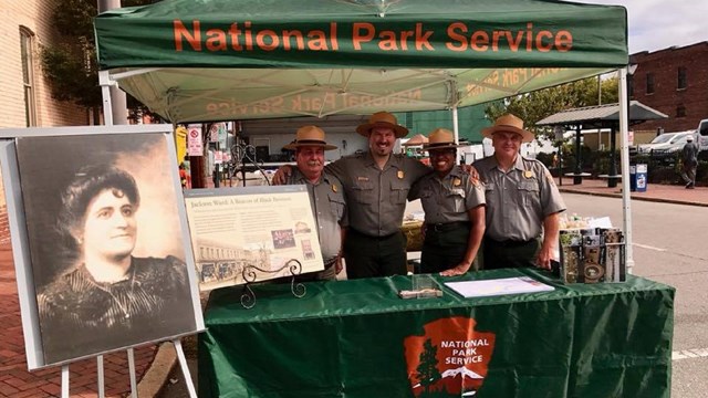 Four rangers standing underneath a tent at a festival.