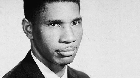 Black and white photo portrait of Medgar Evers in dark suit