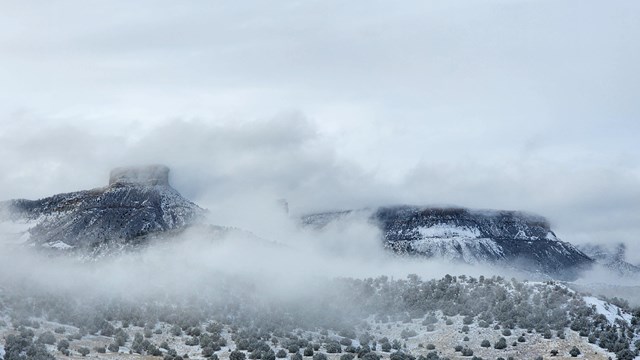 a dusting of snow on a high desert landscape where clouds frame the mesas