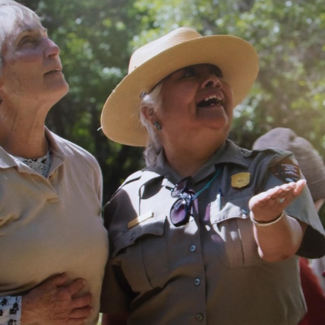 A ranger and a scientist smile in wonder as they release a hummingbird