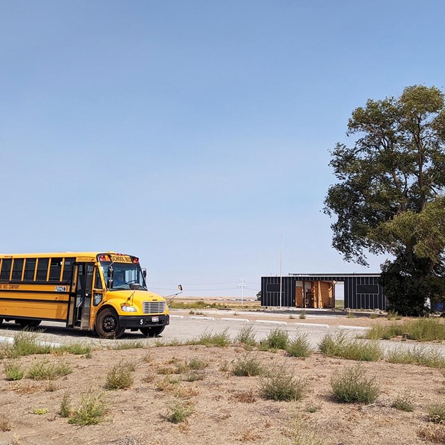 A yellow school bus is parked in front of the Minidoka Visitor Center.