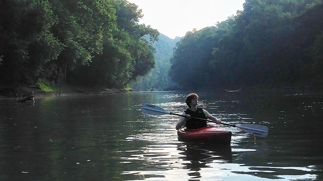 Man in kayak floats on smooth water.