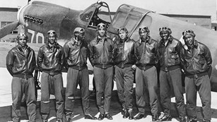 World War II Tuskegee Airmen standing in front of plane.