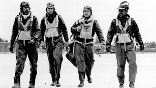 4 african american world war ii pilots walk on a runway