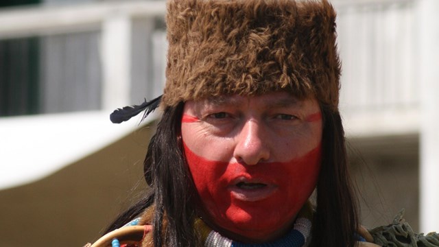 a native american in traditional dress and with face paint on