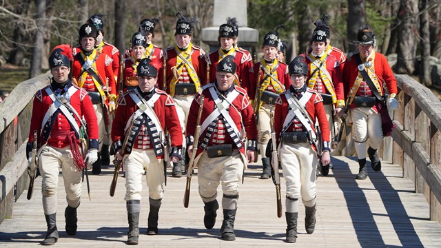 British soldiers march over the North Bridge as the 1836 monument towers behind them.