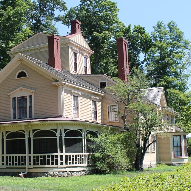 A large yellow house with multiple additions including a 3 story tower and a wrap around porch.