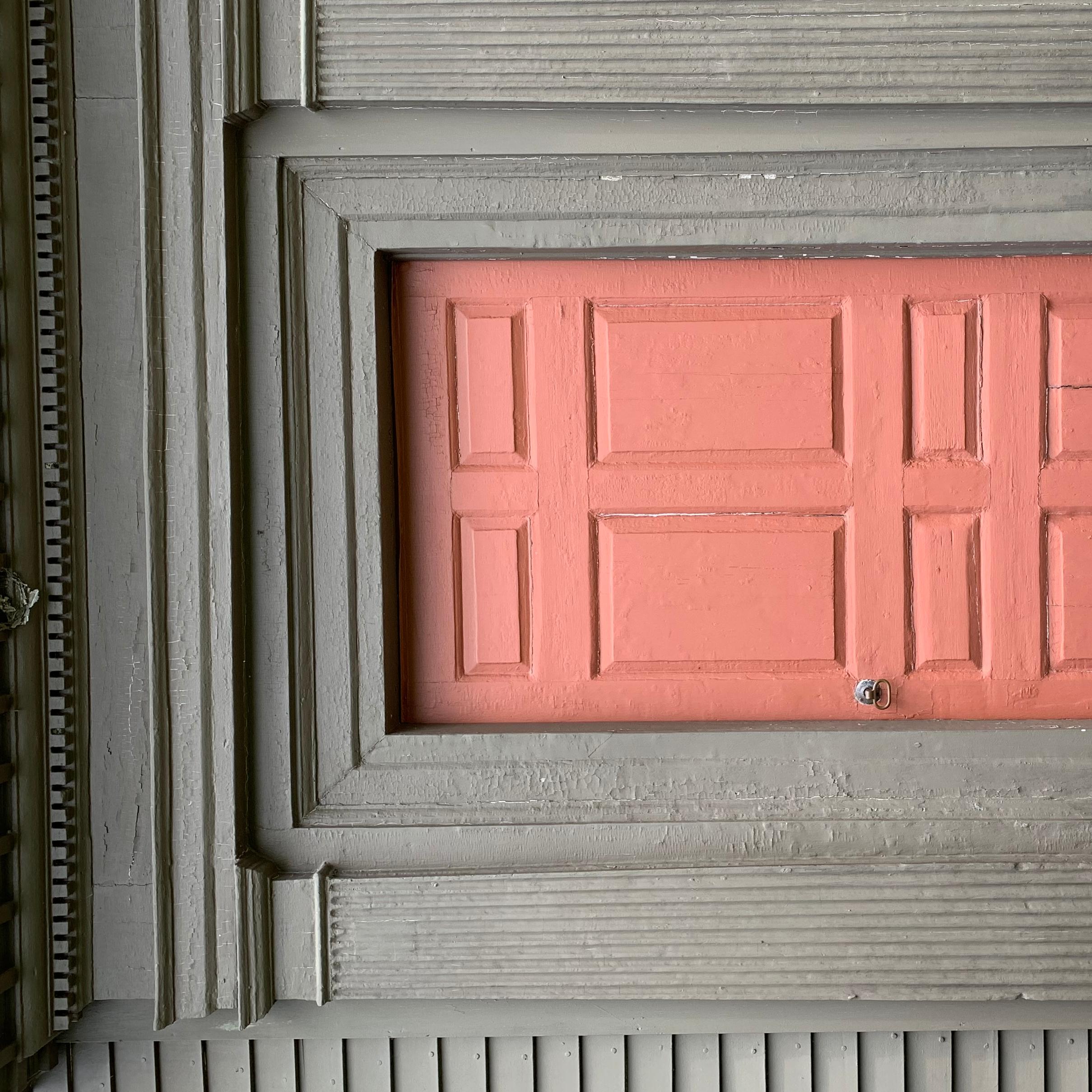 Red wooden door framed with wide wooden pediments painted brown