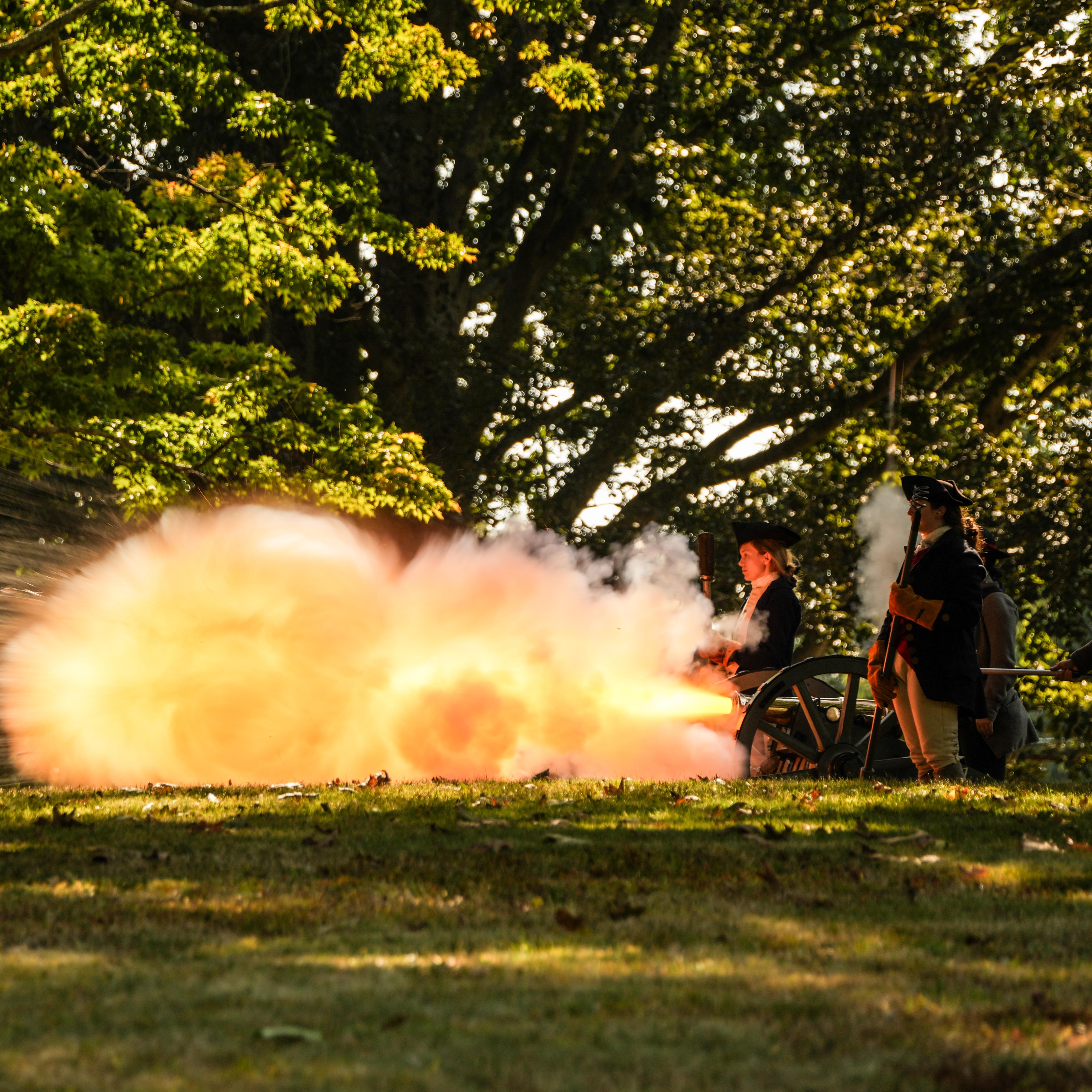 A large flash of fire comes from the front of a cannon.