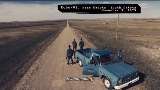 Screenshot showing airmen standing on a dirt road