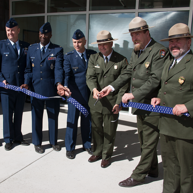 Air Force officers and park rangers cut a ribbon in front of the visitor center