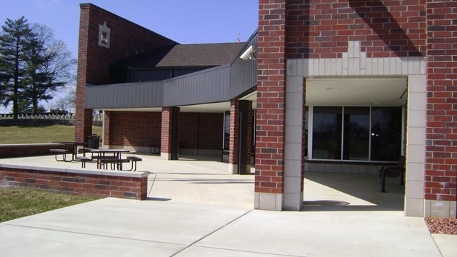 Paved patio with picnic tables outside brick visitor center