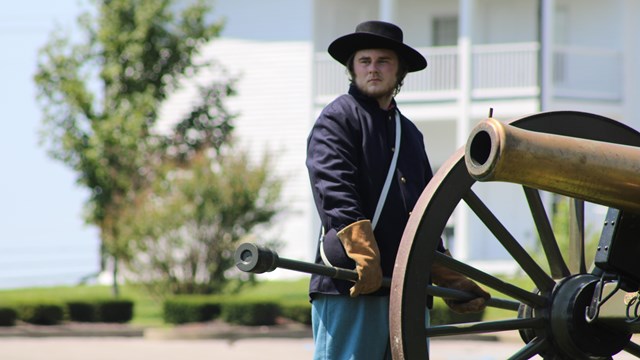 Person wearing a Union uniform standing next to a Civil War Cannon.