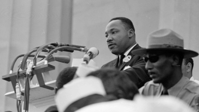 Black and white photo of Dr. Martin Luther King Jr. at a podium and park ranger in the foreground
