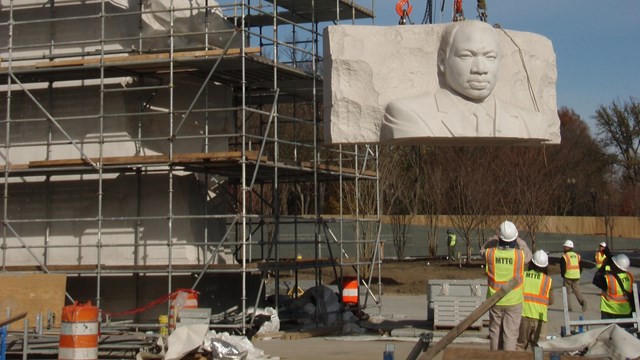 Crane lifting part of the statue of Martin Luther King Jr. during construction
