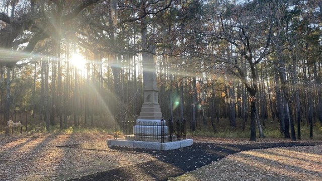 Patriot monument on a Fall day with the sun shining though trees