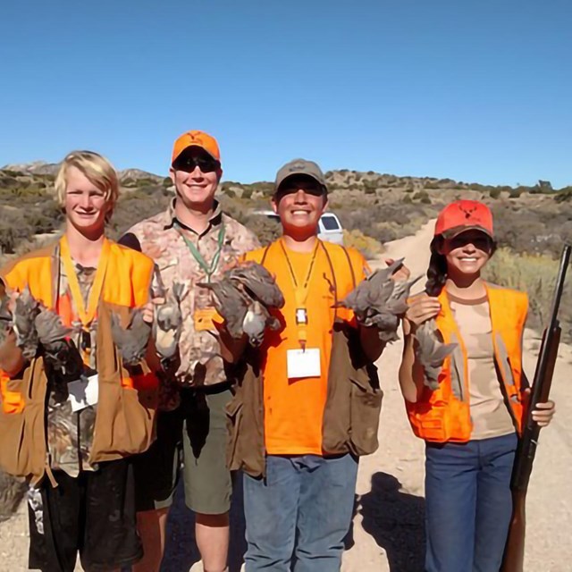 4 youth in orange vests display they quail catch