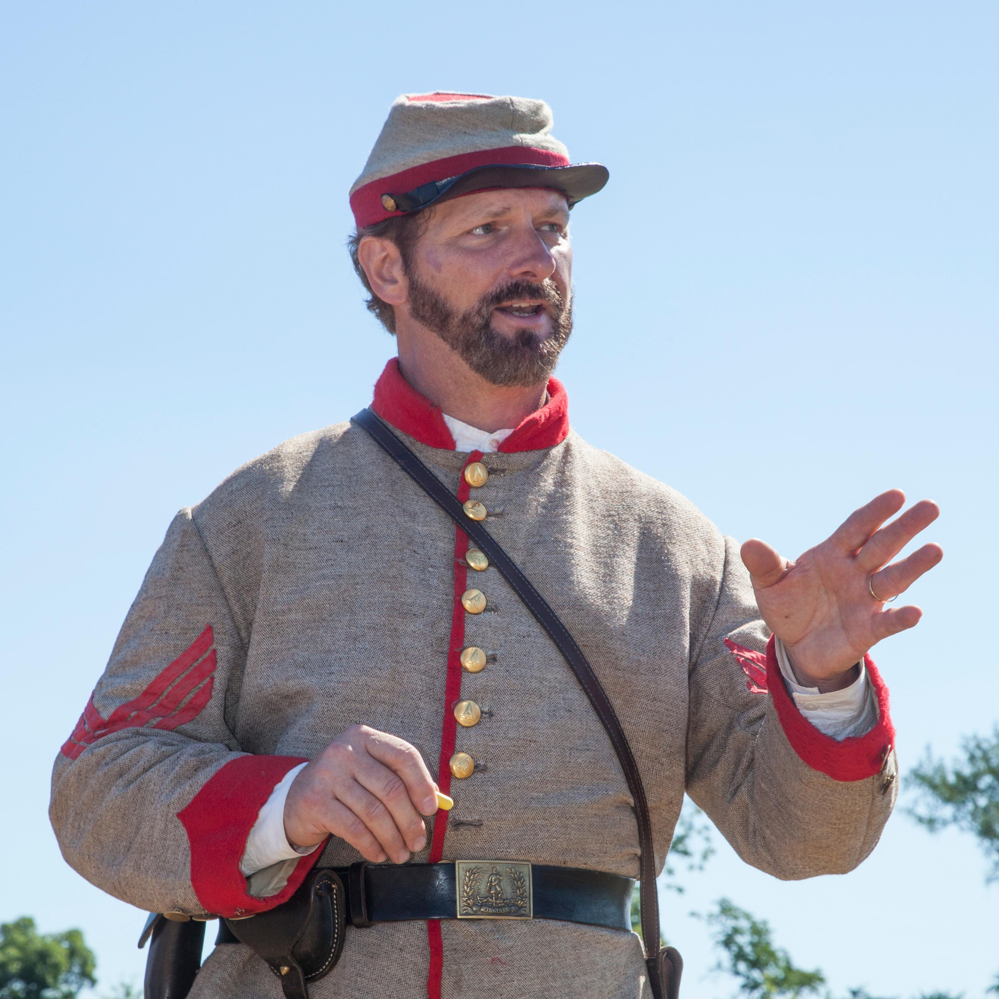 A man in a gray uniform with red trim tells a story.