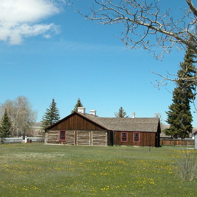 A historic wooden fort sits in a grassy field.