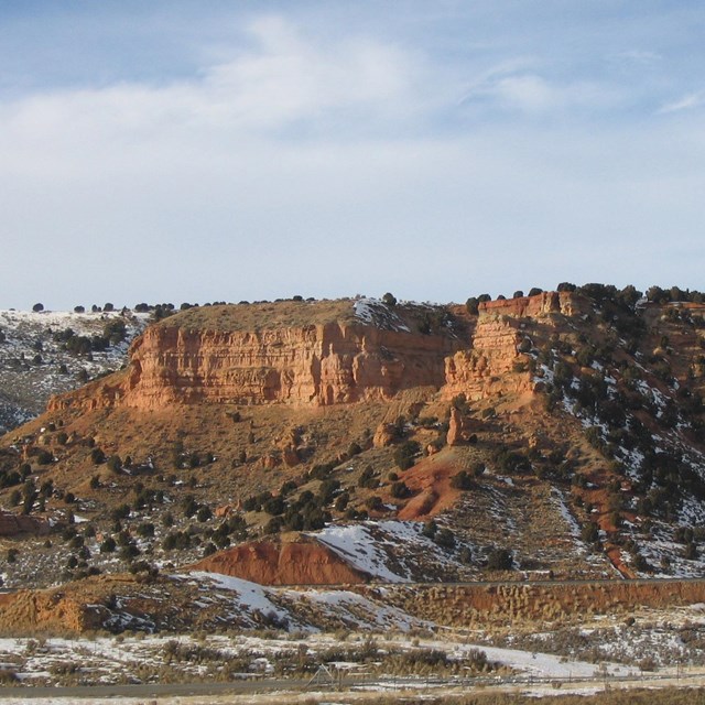 Towering sandstone cliffs, dusted with snow, line a canyon.