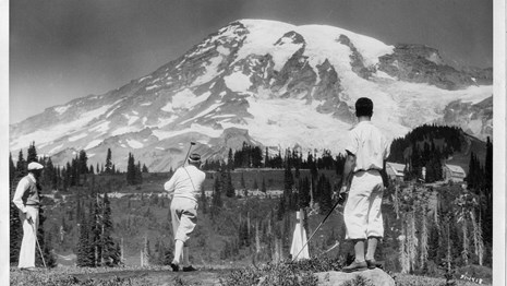 Men playing golf in subalpine meadows with Mount Rainier looming in the background