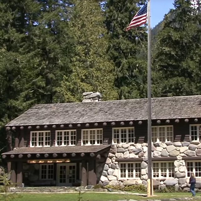 A two story rock and wood building surrounded by forest. 