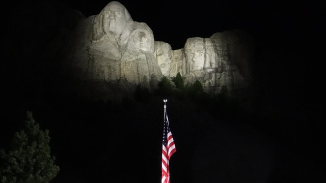 U.S. flag in front of Mount Rushmore at night