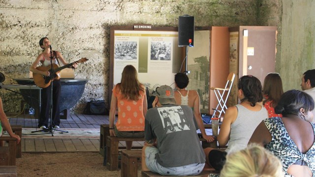 a woman sings with a guitar in front of an audience