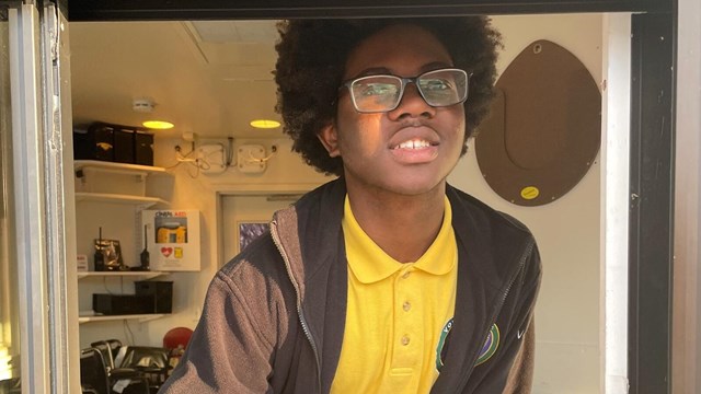 Youth Volunteer handing out brochures from a kiosk