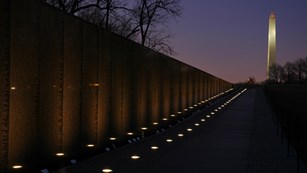 Vietnam Veterans Memorial at night, with Washington Monument in the background