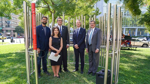 Five people stand in a park surrounded by metal art. 