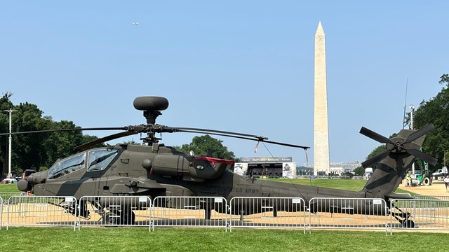 Helicopter on a grassy area with Washington Monument in the distance.