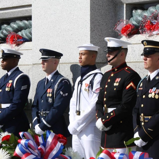US military service members standing in front of a memorial wall