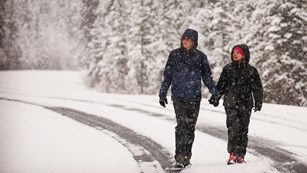 two people walk through the snow