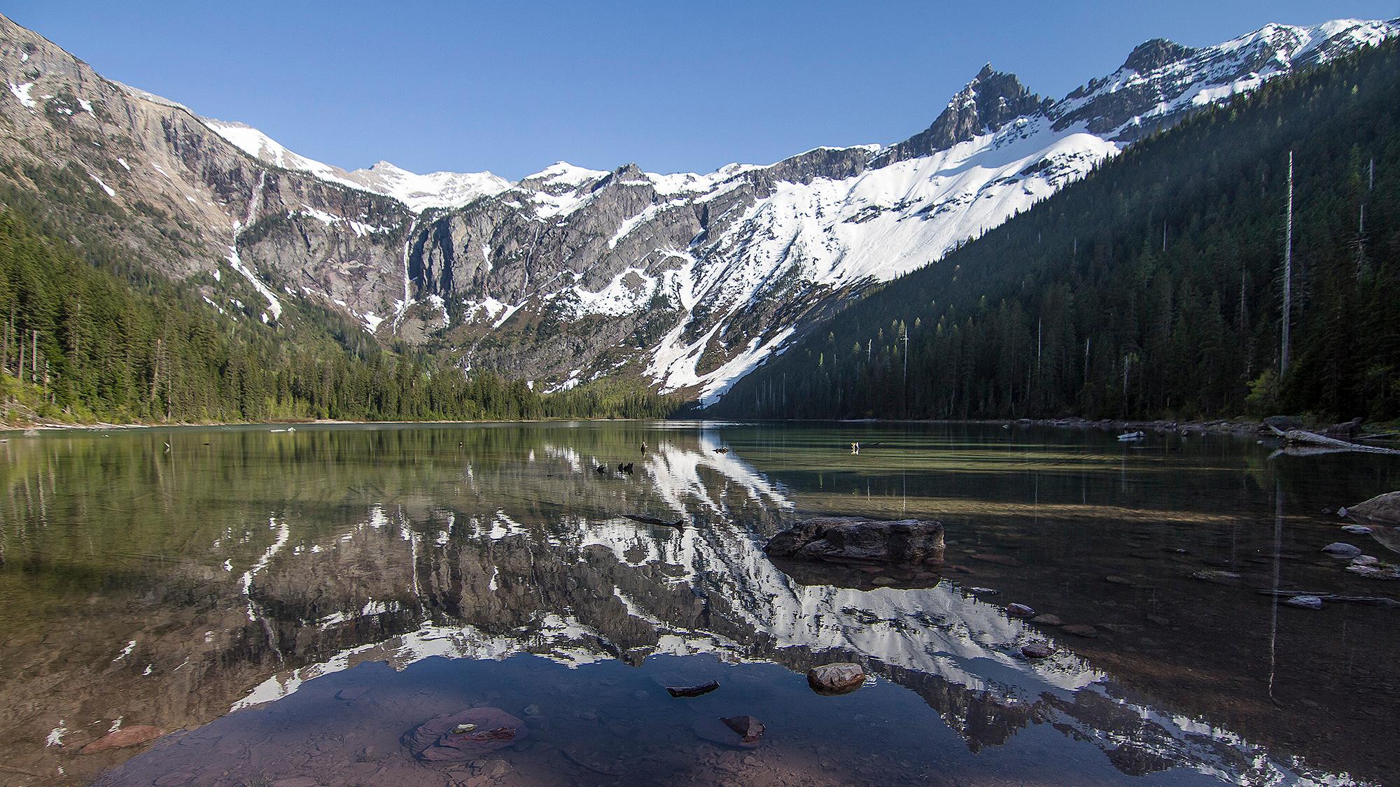 Snow-capped mountains reflect on a mountain lake.