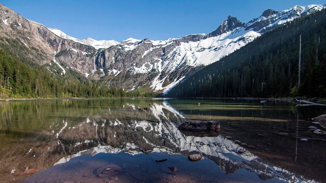 Snow-capped mountains reflect on a mountain lake.