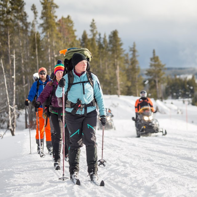 a line of cross country skiers and a snow mobile 