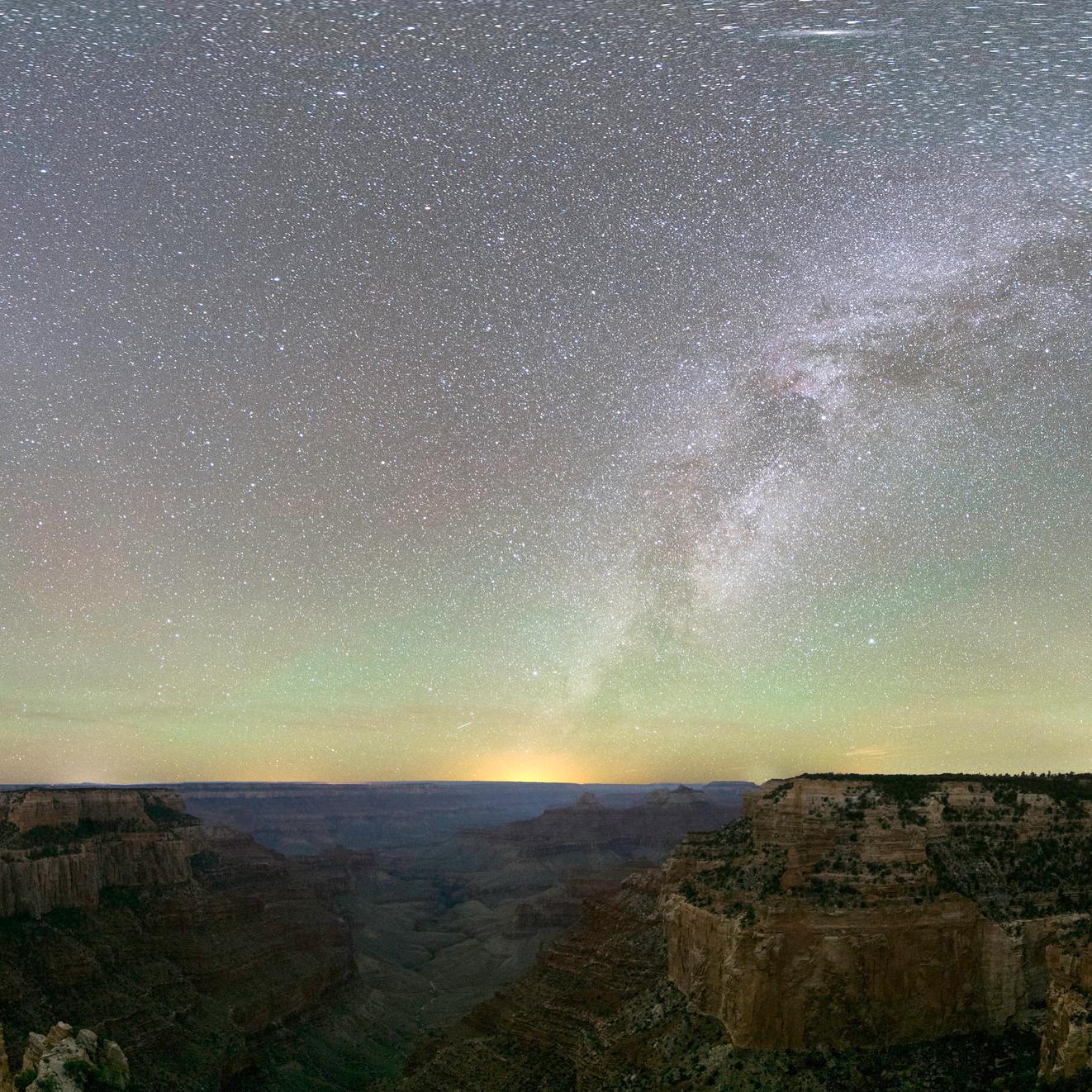 The Milky Way illumines an opalescent night sky over dramatic rock formations