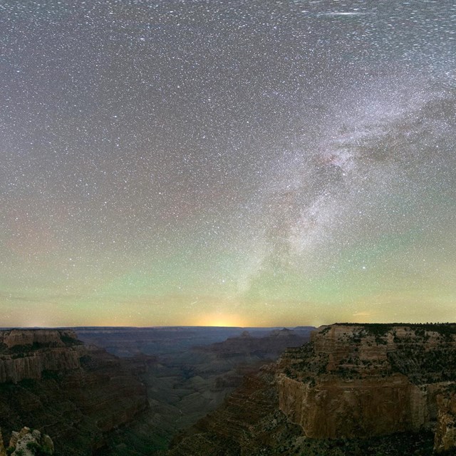 The Milky Way illumines an opalescent night sky over dramatic rock formations