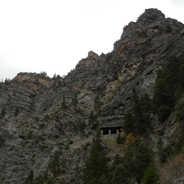 Mountain with small building at cave entrance