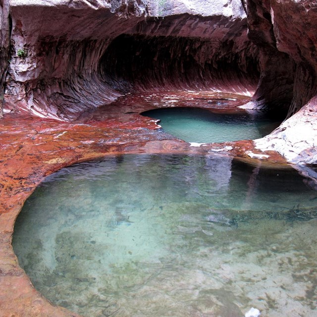 Round pool of green water in redrock canyon
