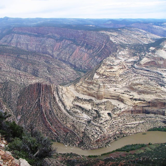 Massive canyon of twisted rock with river in foreground